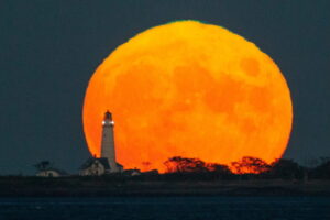Wschodzący Księżyc, pełnia nazywana księżycem plonów albo księżycem kukurydzianym, widoczny za latarnią morską Boston Light, Boston, Massachusetts, USA, 20.09.2021 r. (CJ GUNTHER/PAP/EPA)