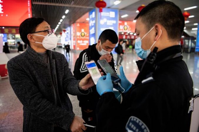 Pasażer okazuje zielony kod QR na swoim telefonie, aby przedstawić ochronie swój stan zdrowia po przybyciu na stację kolejową w Wenzhou, Chiny, 28.02.2020 r. (Noel Celis/AFP via Getty Images)