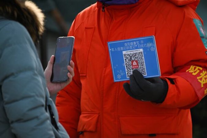 Kobieta używa swojego telefonu komórkowego do zeskanowania kodu QR w celu rejestracji stanu zdrowia przed wejściem na odkryte lodowisko w Pekinie, 12.01.2021 r. (Wang Zhao/AFP via Getty Images)