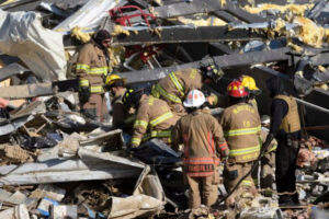 Pracownicy służb ratunkowych przeszukują ruiny fabryki świec Mayfield Consumer Products po tym, jak została zniszczona przez tornado, Mayfield, Kentucky, 11.12.2021 r. (John Amis/AFP via Getty Images)