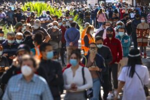 Ludzie w maskach na twarzach stoją w kolejce, oczekując na zaszczepienie w Centrum Szczepień w Sydney Olympic Park w Homebush, Sydney, Australia, 16.08.2021 r. (David Gray/AFP via Getty Images)