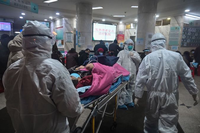 Personel medyczny w odzieży ochronnej mającej zabezpieczyć przed zarażeniem się COVID-19 od przewożonego pacjenta, Szpital Czerwonego Krzyża w Wuhan, Chiny, 25.01.2020 r. (Hector Retamal/AFP via Getty Images)