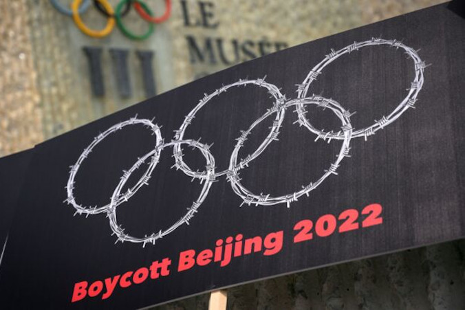 Tablica z drutem kolczastym w kształcie pierścieni olimpijskich widoczna obok logo Muzeum Olimpijskiego podczas protestu zorganizowanego przez tybetańskich i ujgurskich aktywistów przeciwko Zimowym Igrzyskom Olimpijskim Pekin 2022, Lozanna w Szwajcarii, 23.06.2021 r. (Fabrice Coffrini/AFP via Getty Images)