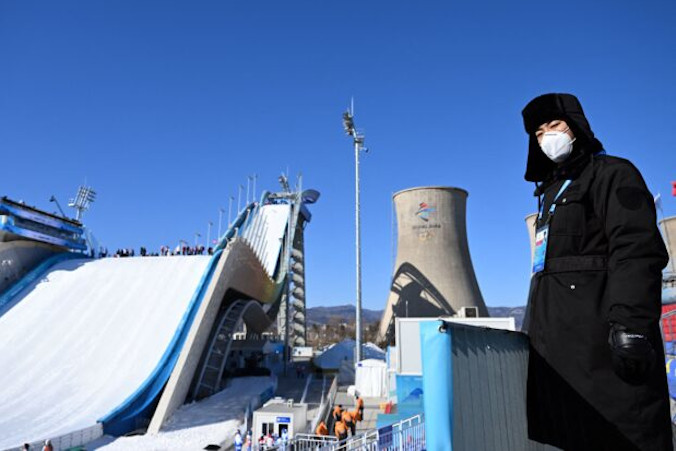 Pracownik chińskiej ochrony przed obiektem Big Air Shougang w Pekinie w przeddzień rozpoczęcia Zimowych Igrzysk Olimpijskich Pekin 2022, 3.02.2022 r. (Manan Vatsyayana/AFP via Getty Images)