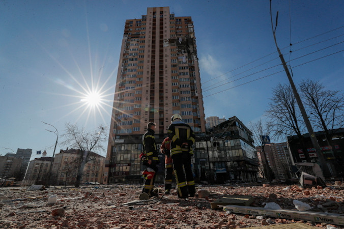 Ukraińscy strażacy stoją przed wieżowcem, w który trafiła rosyjska rakieta podczas ostrzału miasta, Kijów, Ukraina, 26.02.2022 r. (SERGEY DOLZHENKO/PAP/EPA)