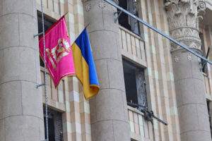 Ukraińska flaga narodowa na budynku administracyjnym zniszczonym w następstwie rosyjskiego ostrzału w Charkowie, Ukraina, 1.03.2022 r. (SERGEY KOZLOV/PAP/EPA)