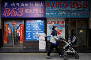 Kobieta z dzieckiem przechodzi obok witryn sklepowych z napisami w cyrylicy w centrum handlowym znanym pod nazwą Rosyjski Market, Pekin, 3.03.2022 r. (Noel Celis/AFP via Getty Images)