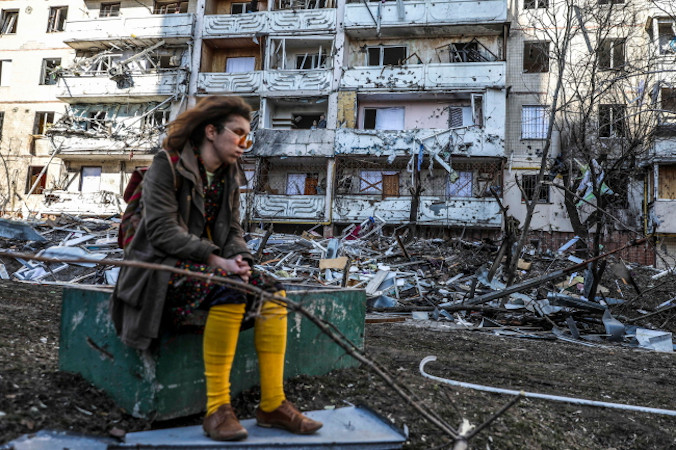 Dziewczyna siedzi obok gruzów budynku uszkodzonego w wyniku ostrzału, Kijów, Ukraina, 15.03.2022 r. (MIGUEL A. LOPES/PAP/EPA)