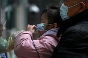 Pracownik służby zdrowia pobiera próbkę wymazu od dziewczynki, która ma zostać przebadana na obecność koronawirusa wywołującego COVID-19 w związku z rekordowym wzrostem liczby zakażeń w Chinach, Pekin, 14.03.2022 r. (Noel Celis/AFP via Getty Images)