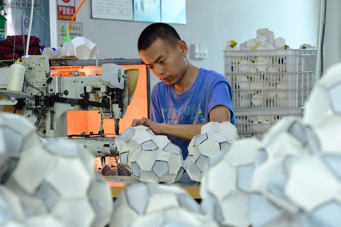 Pracownik produkuje piłki do piłki nożnej, które będą eksportowane do Rosji i Brazylii, fabryka w Yiwu, chińska prowincja Zhejiang, 5.07.2018 r. (-/AFP/Getty Images)
