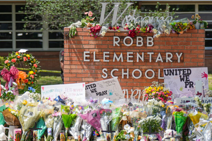 Prowizoryczny pomnik przy Robb Elementary School wypełniony kwiatami, zabawkami, znakami i krzyżami z nazwiskami 21 ofiar masowej strzelaniny, która miała miejsce 24 maja w Uvalde w Teksasie, 27.05.2022 r. (Charlotte Cuthbertson / The Epoch Times)