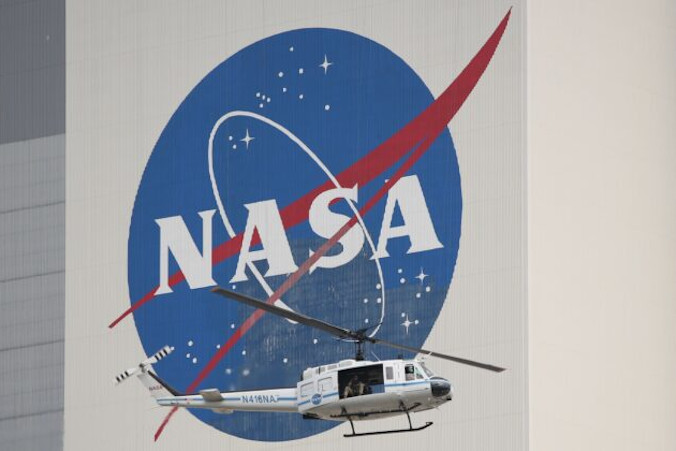 Śmigłowiec służb bezpieczeństwa NASA przelatuje obok Budynku Montowania Pojazdów, ang. Vehicle Assembly Building, w dniu startu w Centrum Kosmicznym Kennedy’ego na Florydzie, 26.05.2020 r. (GREGG NEWTON/AFP via Getty Images)