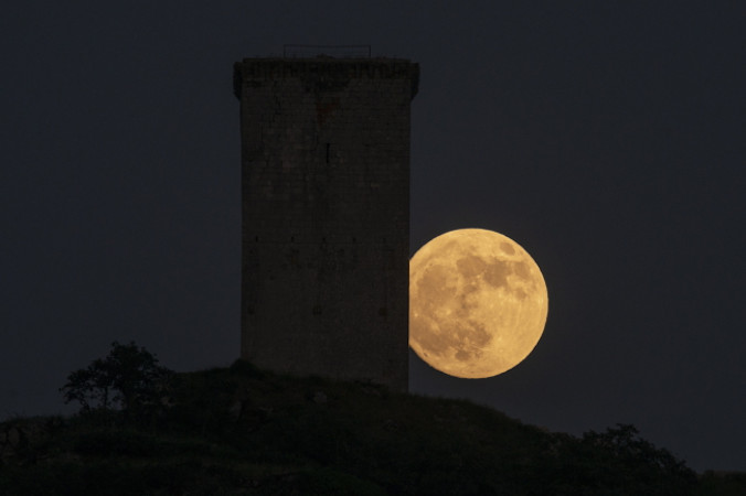 Ostatnia pełnia tej wiosny, znana również jako truskawkowy księżyc, widziana obok Wieży Da Pena w Xinzo de Limia w północnej Hiszpanii, 13.06.2022 r. (Brais Lorenzo/PAP/EPA)