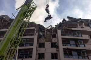Ratownicy w akcji obok uszkodzonego budynku mieszkalnego po rosyjskich nalotach w dzielnicy Szewczenkiwskiej w Kijowie, Ukraina, 26.06.2022 r. (ROMAN PILIPEY/PAP/EPA)