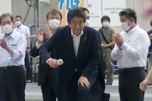 Były premier Japonii Shinzō Abe (pośrodku) staje na podium, aby przemówić do wyborców w celu wsparcia kandydata swojej partii podczas kampanii wyborczej do izby wyższej parlamentu, przed stacją Yamato-Saidaiji sieci kolei Kintetsu, miasto Nara, na zachodzie Japonii; tuż przed tym, jak został postrzelony przez zamachowca, 8.07.2022 r. (JIJI PRESS/PAP/EPA)