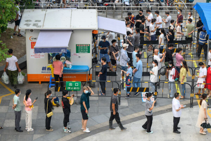 Mieszkańcy stoją w kolejce, aby poddać się testom na COVID-19 wykrywającym obecność kwasu nukleinowego, miejsce pobierania wymazów w mieście Guangzhou (Kanton), w prowincji Guangdong na południu <a href="https://www.theepochtimes.com/t-china">Chin</a>, 31.07.2022 r. (STR/AFP via Getty Images)