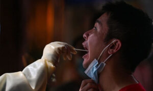 Pracownik służby zdrowia pobiera próbkę wymazu od mężczyzny w celu przeprowadzenia testu na obecność COVID-19, dzielnica Jing’an w Szanghaju, Chiny, 31.07.2022 r. (Hector Retamal/AFP via Getty Images)