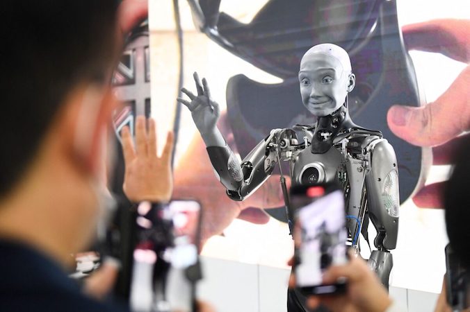 Uczestnicy robią zdjęcia i wchodzą w interakcje z wyposażonym w sztuczną inteligencję robotem humanoidalnym Engineered Arts Ameca, prezentowanym podczas Consumer Electronics Show (CES) w Las Vegas, stan Nevada, Stany Zjednoczone, 5.01.2022 r. (Patrick T. Fallon/AFP via Getty Images)