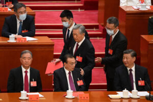 Przywódca Chin Xi Jinping (po prawej) patrzy, jak były przywódca Hu Jintao (pośrodku), który opuszcza ceremonię zamknięcia XX zjazdu Komunistycznej Partii Chin, dotyka ramienia premiera Li Keqianga (drugi po lewej), Wielka Hala Ludowa w Pekinie, 22.10.2022 r. (Noel Celis/AFP via Getty Images)