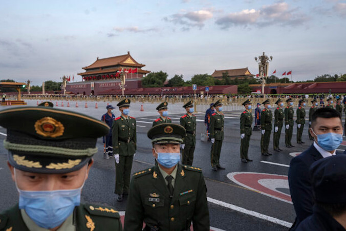 Policjanci i ochrona kontrolują tłum po oficjalnej ceremonii podniesienia flagi z okazji święta narodowego obok placu Tiananmen i Zakazanego Miasta w Pekinie, Chiny, 1.10.2021 r. (Kevin Frayer / Getty Images)