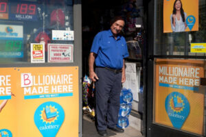 Joe Chahayed przy drzwiach swojego sklepu Joe’s Service Center, gdzie sprzedano rekordowy zwycięski los Powerball o wartości 2,04 mld dolarów, Altadena w Kalifornii, USA, 09.11.2022 r. Napis w reklamie loterii po lewej stronie został zmieniony na „miliarder” (ALLISON DINNER/PAP/EPA)