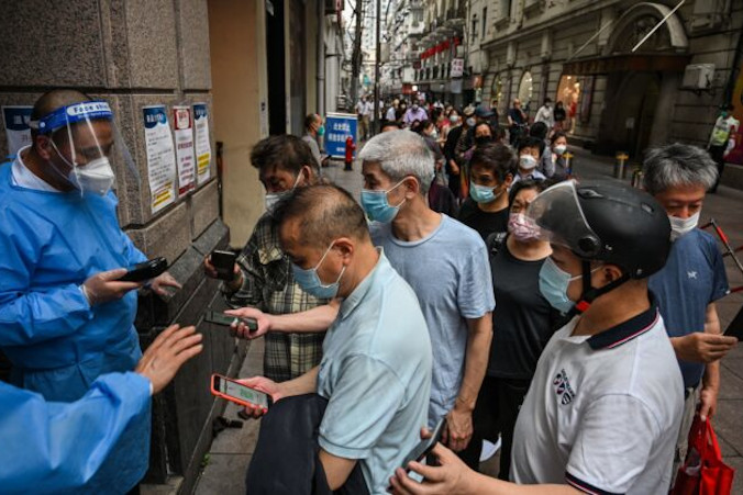Pracownicy skanują kody QR dotyczące zdrowia osób wchodzących do centrum handlowego w dzielnicy Huangpu w Szanghaju, 1.06.2022 r. (Hector Retamal/AFP via Getty Images)