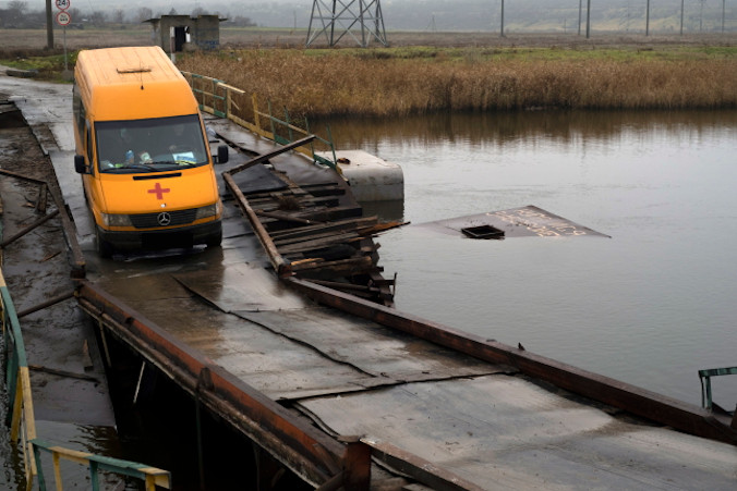 Samochód wolontariuszy jedzie po uszkodzonym moście przez rzekę Ingulec na wschód od Chersonia, Ukraina, 20.11.2022 r., wydane 21.11.2022 r. (GEORGE IVANCHENKO/PAP/EPA)