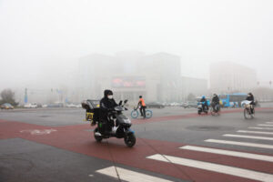 Ludzie noszą maski, gdy przemieszczają się ulicą podczas smogu, Pekin, Chiny, 18.11.2021 r. (Lintao Zhang / Getty Images)