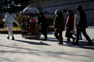 Członkowie rodziny podążają za urną z prochami bliskiej osoby na terenie krematorium w Pekinie, 22.12.2022 r. (STF/AFP via Getty Images)