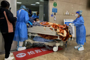 Pracownicy służby zdrowia przewożą pacjenta z COVID-19 na noszach na oddziale ratunkowym Pierwszego Szpitala Stowarzyszonego Uniwersytetu Medycznego Chongqing w Chongqing, Chiny, 22.12.2022 r. (Noel Celis/AFP via Getty Images)