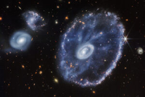 Galaktyka Koło Wozu to galaktyka pierścieniowa znajdująca się ok. 500 mln lat świetlnych stąd, w gwiazdozbiorze Rzeźbiarza. Tutaj pokazano ją w bliskiej podczerwieni, uchwyconą przez Kosmiczny Teleskop Jamesa Webba. Teleskop wykonał również zdjęcie w średniej podczerwieni, a także połączenie tych dwóch obrazów (<a href="https://stsci-opo.org/STScI-01G9G4KWCB7CHGD6Z1A26G9CVT.png">NASA, ESA, CSA, STScI</a> / <a href="https://commons.wikimedia.org/w/index.php?curid=121467324">domena publiczna</a>)