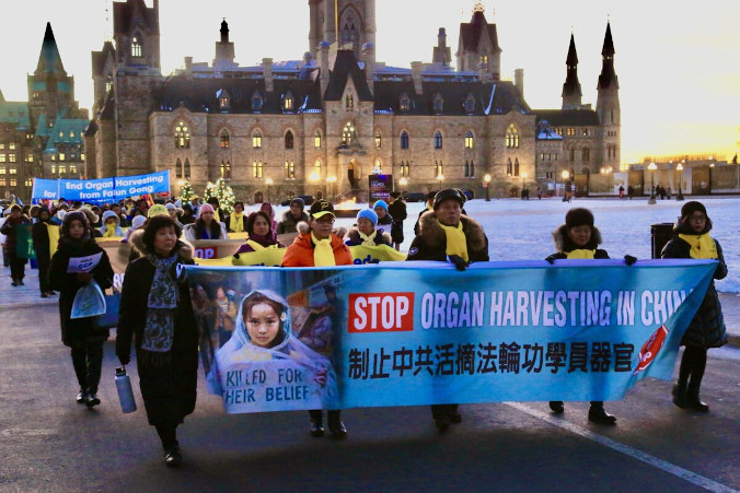 Praktykujący Falun Gong, trzymając transparenty, maszerują do ambasady Chin w Ottawie, aby świętować sukces przyjęcia projektu ustawy S-223, mającej na celu zwalczanie grabieży organów, 14.12.2022 r. (Jian Ren / The Epoch Times)