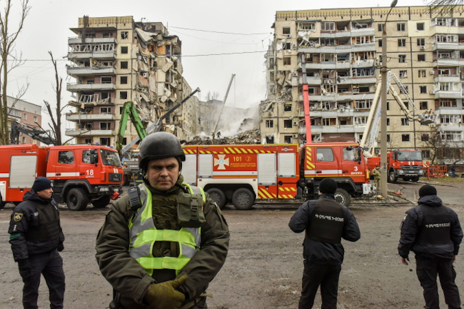 Funkcjonariusze Gwardii Narodowej Ukrainy i policjanci czuwają w pobliżu zniszczonego budynku mieszkalnego w Dnieprze, Ukraina, 15.01.2023 r. (PAP/EPA)