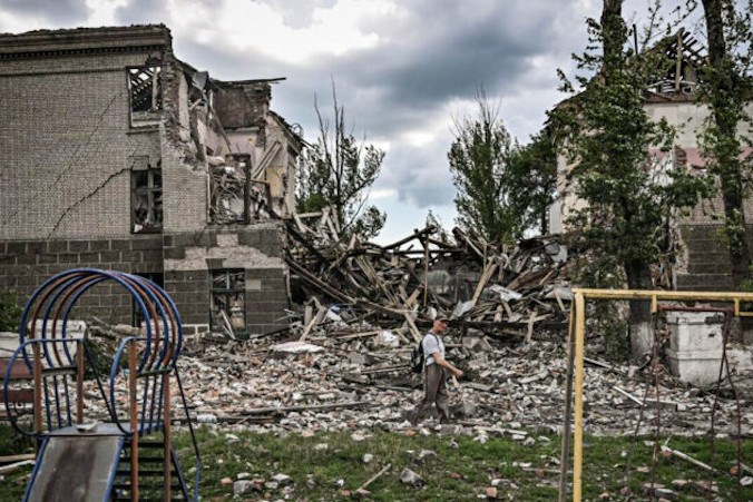 Mężczyzna spaceruje przed zniszczoną szkołą w mieście Bachmut, region Donbas na wschodzie Ukrainy, 28.05.2022 r. (Aris Messinis/AFP via Getty Images)