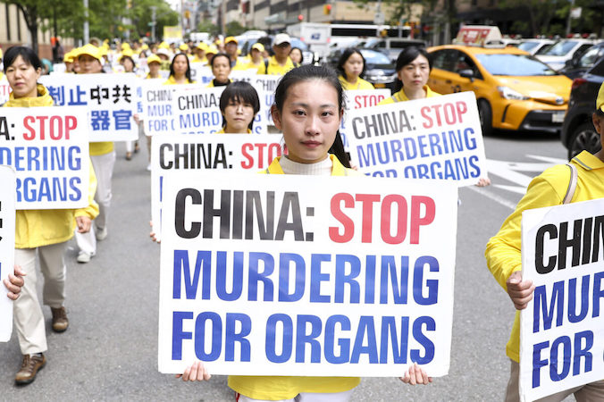 Praktykujący Falun Dafa trzymają plakaty podczas parady, która ma na celu zwiększenie świadomości na temat prześladowań praktyki w Chinach, Manhattan, Nowy Jork, 16.05.2019 r. (Samira Bouaou / The Epoch Times)