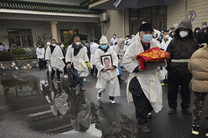 Żałobnik niesie skremowane szczątki bliskiej osoby. Osoby na zdjęciu ubrane są w tradycyjne białe szaty pogrzebowe, Szanghaj, Chiny, zdjęcie archiwalne (Kevin Frayer / Getty Images)
