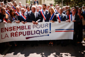 Burmistrz L’Haÿ-les-Roses Vincent Jeanbrun (pośrodku, z szarfą), towarzyszy mu przewodniczący Senatu Francji Gérard Larcher (pośrodku po lewej, bez szarfy) i przewodnicząca Rady Regionalnej île-de-France Valérie Pecresse (po środku po prawej), trzyma transparent z napisem „Razem dla Republiki” podczas wiecu obywatelskiego po ataku na jego dom w L’Haÿ-les-Roses, na południe od Paryża, Francja, 3.07.2023 r. Stowarzyszenie Burmistrzów Francji (Association des Maires de France) wezwało burmistrzów kraju, obywateli i wybranych urzędników do zorganizowania wieców przeciwko przemocy przed ratuszami po dniach gwałtownych protestów po śmiertelnym postrzeleniu nastolatka w Nanterre podczas zatrzymania przez policję (YOAN VALAT/PAP/EPA)