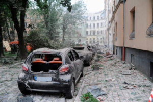 Uszkodzone pojazdy i gruz na ulicy w miejscu uderzenia rakiety w blok mieszkalny we Lwowie, Ukraina, 6.07.2023 r. (MYKOLA TYS/PAP/EPA)