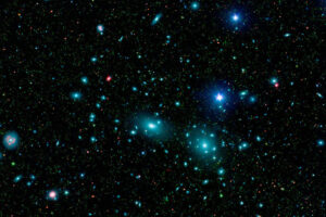 Na zdjęciu ilustracyjnym sztucznie pokolorowana mozaika centralnego obszaru gromady Coma łączy obrazy w podczerwieni i świetle widzialnym, aby ukazać tysiące słabych obiektów (kolor zielony). Dalsze obserwacje wykazały, że wiele z tych obiektów, które pojawiają się tutaj jako słabe zielone smugi, to galaktyki karłowate należące do gromady. Dwie duże galaktyki eliptyczne NGC 4889 i NGC 4874 dominują w centrum gromady. Mozaika łączy dane światła widzialnego z Sloan Digital Sky Survey (oznaczone kolorem niebieskim) z widokami w podczerwieni o długiej i krótkiej długości fali (odpowiednio czerwone i zielone) z Kosmicznego Teleskopu Spitzera NASA (<a href="https://www.spitzer.caltech.edu/image/ssc2007-10a1-dwarf-galaxies-in-the-coma-cluster">NASA/JPL-Caltech/L. Jenkins, GSFC</a> / <a href="https://commons.wikimedia.org/w/index.php?curid=2182745">domena publiczna</a>)