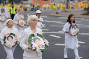 Praktykujący Falun Dafa niosą zdjęcia ofiar prześladowań w Chinach podczas marszu przez centrum Warszawy, 9.09.2022 r. (Mihut Savu / The Epoch Times)