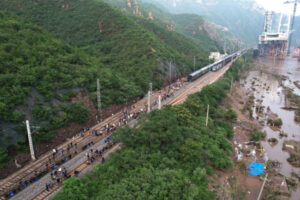 Pasażerowie, którzy utknęli z powodu intensywnych opadów deszczu, idą z pomocą ratowników do innego pociągu, Mentougou na zachód od Pekinu, Chiny, 2.08.2023 r., wydane 3.08.2023 r. Ostatnia grupa pasażerów pociągów Z180 i K396 przybyła na dworzec kolejowy Fengtai w Pekinie we wczesnych godzinach 3 sierpnia (PAP/EPA/XINHUA / Zhang Chenlin)