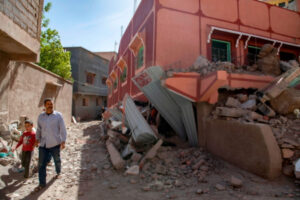 Mężczyzna z dzieckiem przechodzi obok uszkodzonego budynku po trzęsieniu ziemi w Marrakeszu, Maroko, 9.09.2023 r. (JALAL MORCHIDI/PAP/EPA)