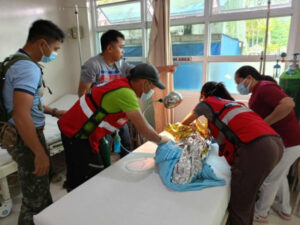 Ratownicy udzielają pomocy medycznej dziecku w wiosce, gdzie nastąpiło osunięcie ziemi, miejscowość Maco w prowincji Davao de Oro na Filipinach, 9.02.2024 r. Zdjęcie udostępnione przez Filipiński Czerwony Krzyż, Philippine Red Cross (PRC/PAP/EPA)