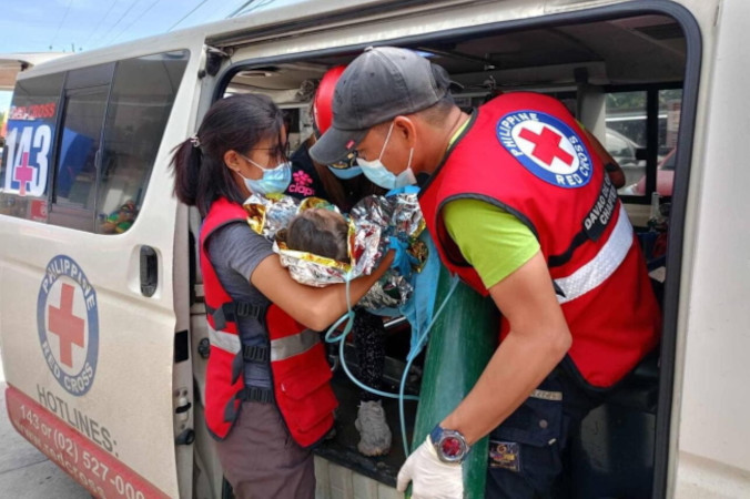 Ratownicy udzielają pomocy medycznej dziecku w wiosce, gdzie nastąpiło osunięcie ziemi, miejscowość Maco w prowincji Davao de Oro na Filipinach, 9.02.2024 r. Dwoje dzieci zostało uratowanych 9 lutego po trzech dniach uwięzienia w osuwisku w wiosce położonej na terenie kopalni w Maco. Zdjęcie udostępnione przez Filipiński Czerwony Krzyż, Philippine Red Cross (PRC/PAP/EPA)