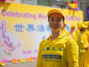 Praktykująca Falun Gong stoi przed banerem podczas corocznego wydarzenia z okazji Światowego Dnia Falun Dafa, Londyn, 11.05.2024 r. (Yanning Qi / The Epoch Times)