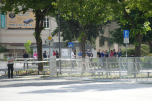 Policjanci i postronne osoby stoją w pobliżu odgrodzonego miejsca, gdzie wcześniej postrzelono słowackiego premiera Roberta Ficę, Handlová na Słowacji, 15.05.2024 r. (JAKUB GAVLAK/PAP/EPA)
