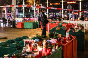 Kwiaty i świece na betonowych blokach chroniących teren jarmarku bożonarodzeniowego w Magdeburgu, Niemcy, 21.12.2024 r. (FILIP SINGER/PAP/EPA)