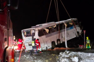 Ciężarówka z dźwigiem podnosi autobus, który zjechał z drogi w Hadsel, Norwegia, 27.12.2024 r. (Jens Andre M. Birkeland/PAP/EPA)